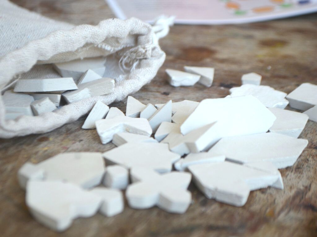 Piezas de arcilla sin pintar saliendo de una bolsa de algodón