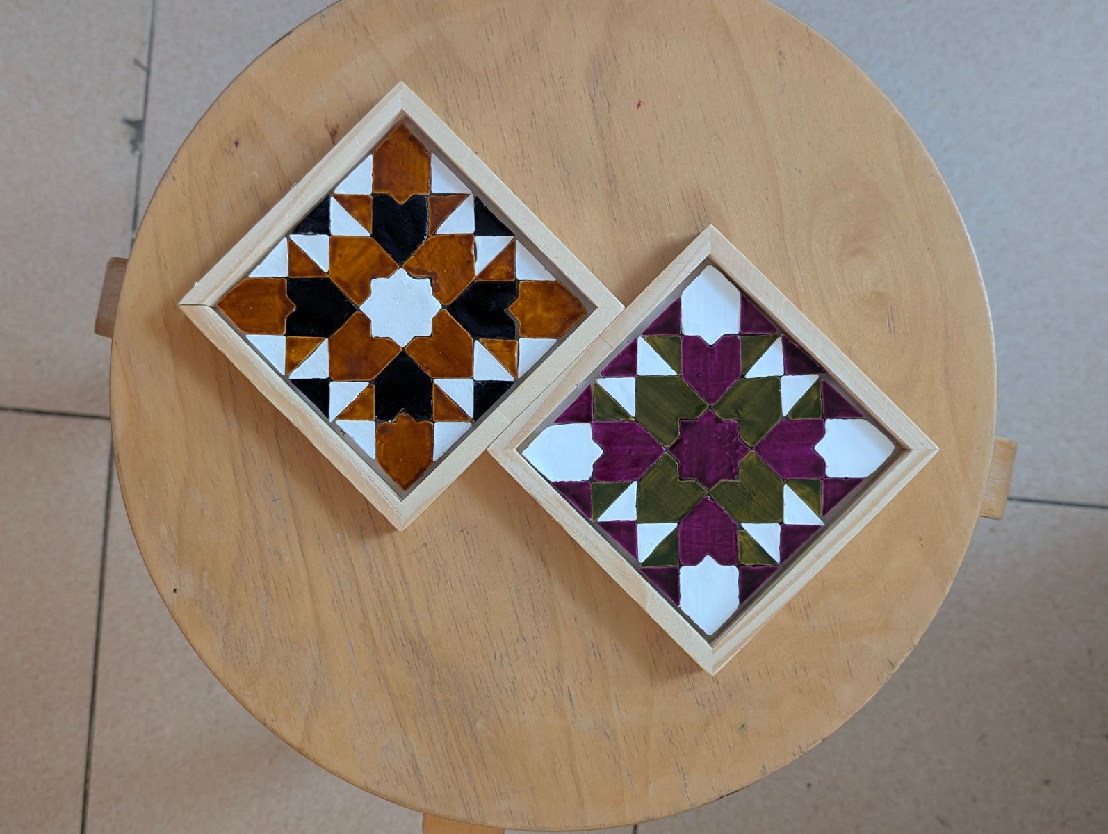 Dos sotagots de mosaic geomètric acabats sobre un tamboret de fusta