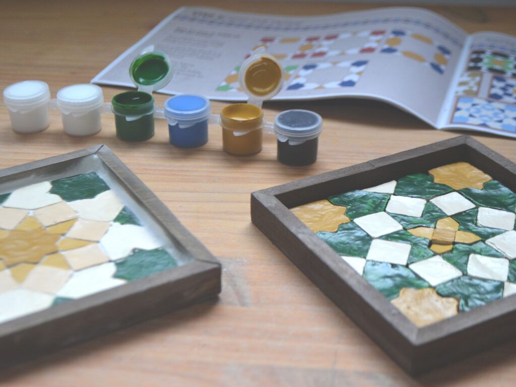 Posavasos terminados delante de los botes de pintura y la guía